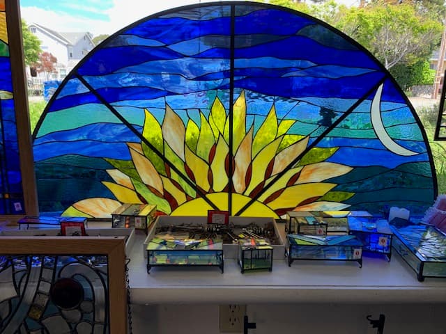 Large arched stained glass sunflower panel in yellow, green, and blue
