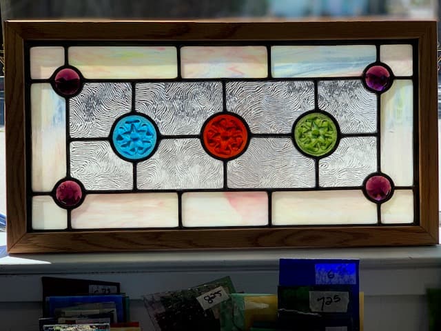 Restored Victorian stained glass panel with decorative roundels in teal, red, and green