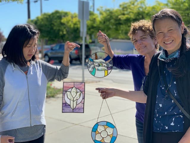 Students proudly displaying their finished stained glass suncatchers after class