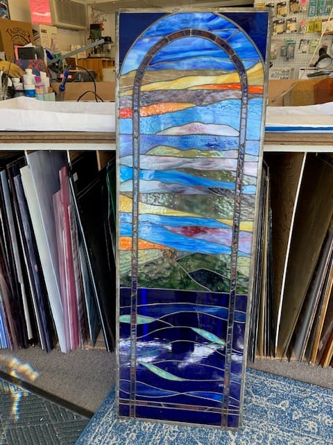Abstract stained glass panel with arched design in blues, oranges, and teal