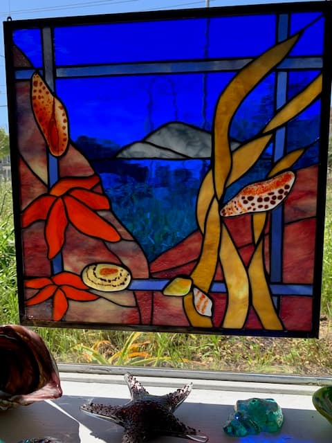 Stained glass underwater ocean scene with kelp, garibaldi fish, and abalone shells