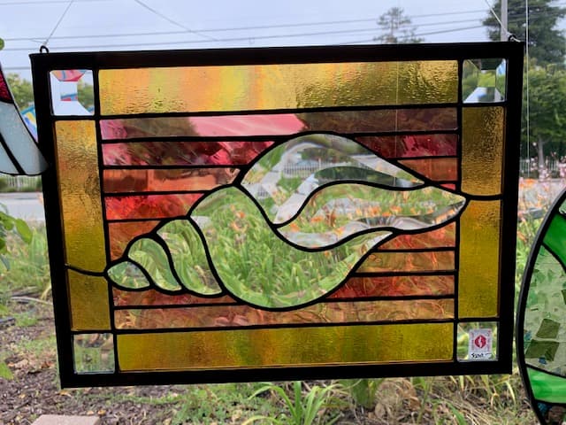 Stained glass conch shell panel in warm amber and gold tones